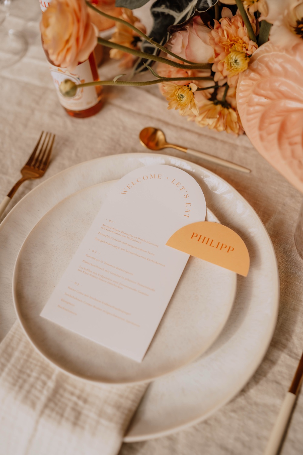 Close-up eines Gedecks mit Menükarte, goldenem Besteck und Musselinserviette